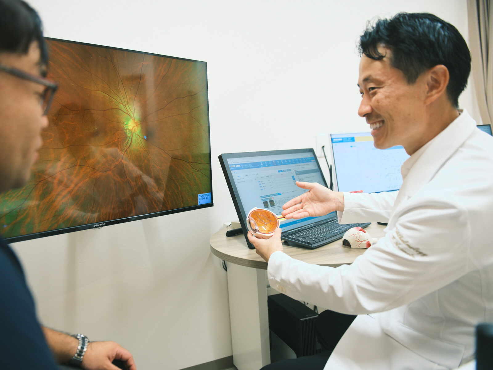 院長が目の画像をモニターに映しながら検査結果を説明する様子