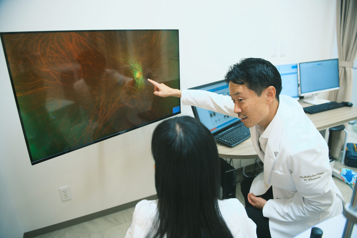 超広角眼底画像をモニターで示しながら説明する院長